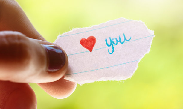 一个十几岁的女孩手里拿着一张纸条，上面写着“爱你”图片下载