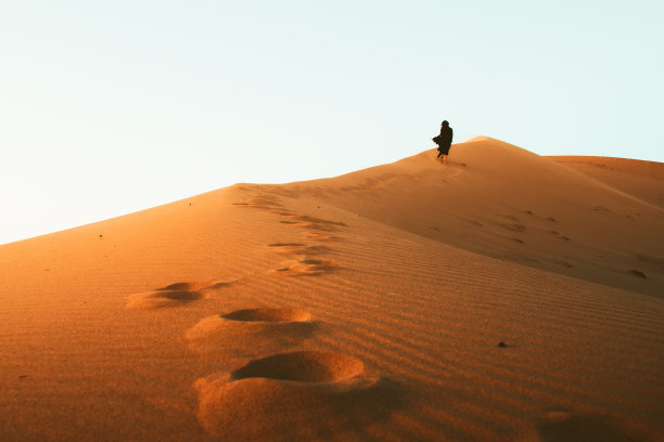 低角度拍摄：赤脚长裙美女在卡尚沙漠沙丘上行走图片下载