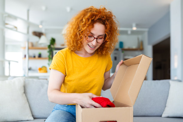 年轻女子在家里收包裹。假日网购和拆纸板箱。covid隔离期间的配送服务。快乐的女孩收到礼物。生活的时刻图片下载