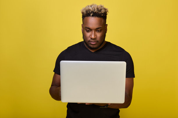 照片中，一位皮肤黝黑的商人正严肃地看着笔记本电脑屏幕。图片下载