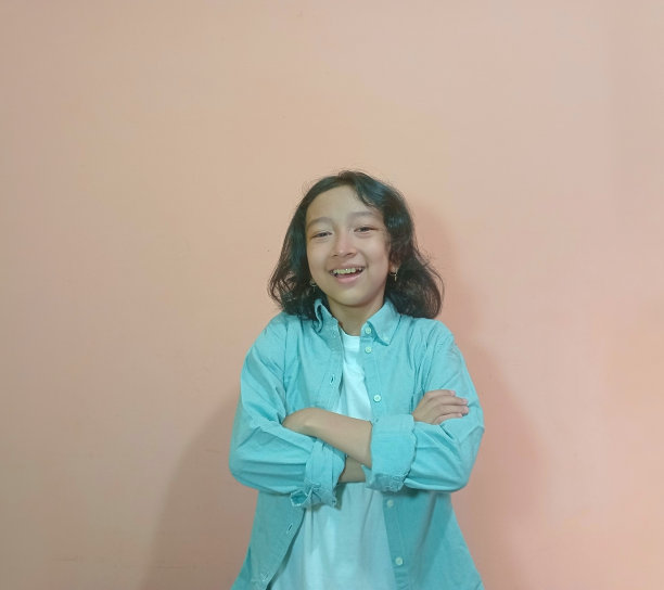 一个小女孩的肖像正交叉着手臂，对着镜头微笑。图片下载