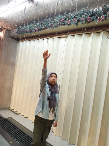 一个十几岁的女孩在一家关闭的商店的折叠门前摆姿势。图片下载