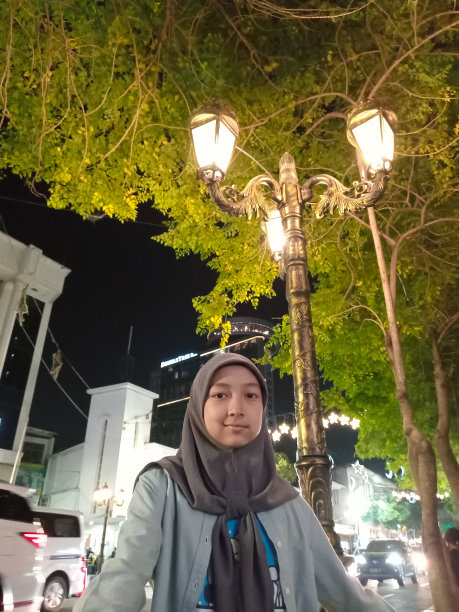 一个十几岁的女孩晚上在树下摆姿势。图片下载