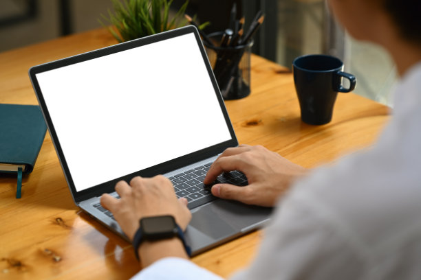 回头看商人双手在笔记本电脑键盘上打字，白色的空白屏幕为您的广告短信。图片下载