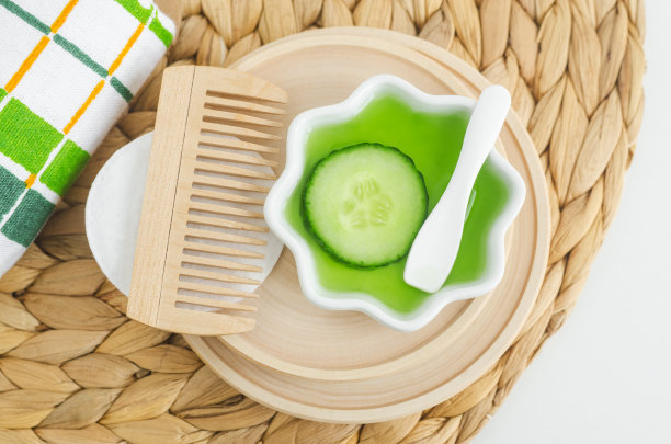 黄瓜片，黄瓜汁和木制发刷。自制面部或头发爽肤水和美容眼膜的原料。天然皮肤护理或头发护理和水疗配方。前视图。图片下载