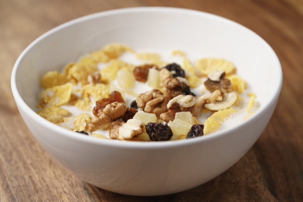 木桌上白色碗里的玉米片、水果和坚果的特写照片图片下载