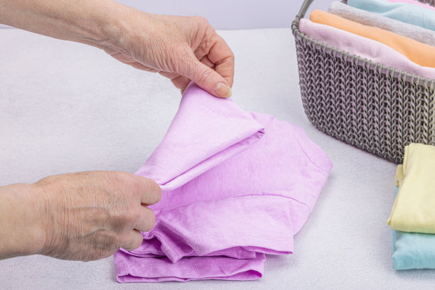 女人的手叠着干净的衣服。垂直存放衣物的篮子。衣柜清洁图片下载