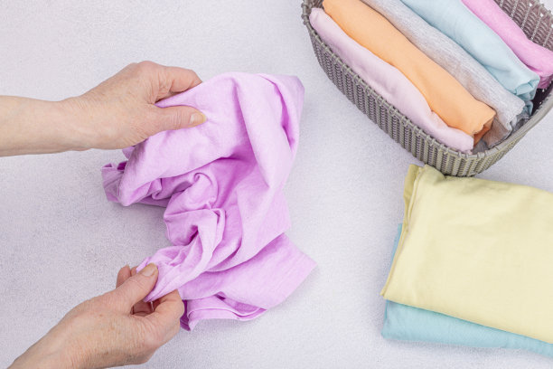 女人的手叠着干净的衣服。垂直存放衣物的篮子。衣柜清洁图片下载
