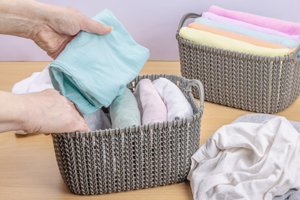 女人的手叠着干净的衣服。垂直存放衣物的篮子。衣柜清洁图片下载