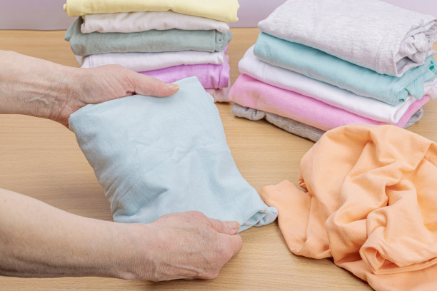 女人的手叠着干净的衣服。垂直存放衣物的篮子。衣柜清洁图片下载