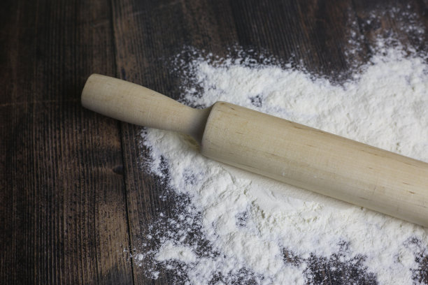 木质的轻擀面杖放在面粉里图片下载