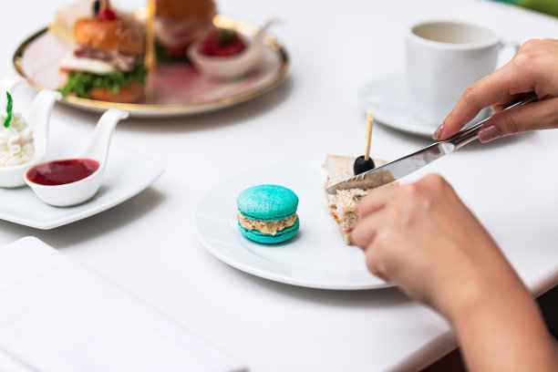 人的手在桌子上切面包，人的手在厨房做饭的玻璃桌子上的特写与反射主妇切面包图片下载