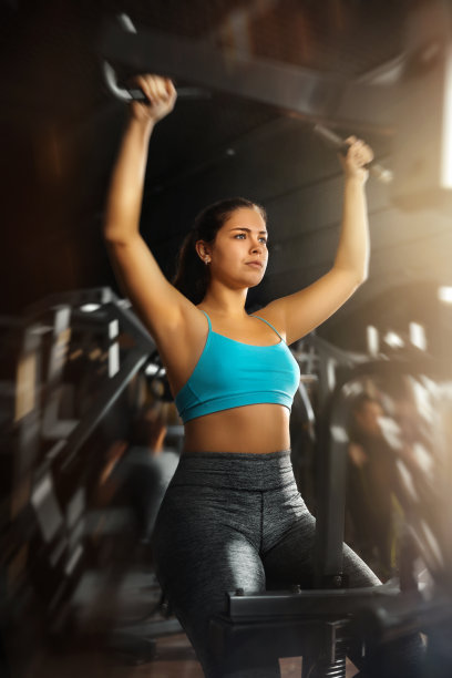 运动女孩在健身器械上表演杠杆下拉图片下载