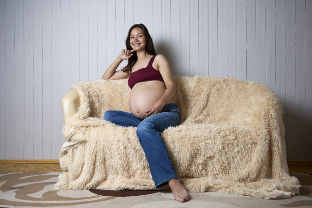 快乐的大肚子孕妇在沙发上摆姿势图片下载