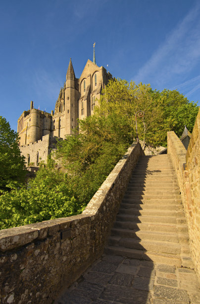 古老狭窄的鹅卵石楼梯通往中世纪的圣米歇尔山修道院。阳光明媚的春日风景照。法国诺曼底。旅游和旅游理念。联合国教科文组织世界遗产图片下载