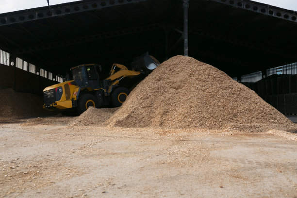 轮式装载机在工厂建造大型木屑储存桩图片下载