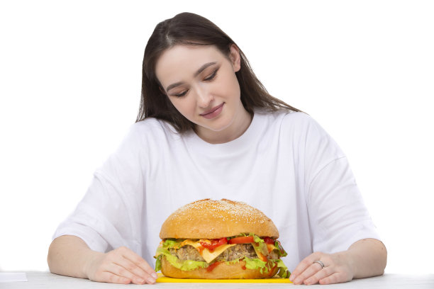 背景上，一个女人拿着一个大的烧烤汉堡三明治。快餐概念。这个女孩有一个巨大的汉堡包。图片下载