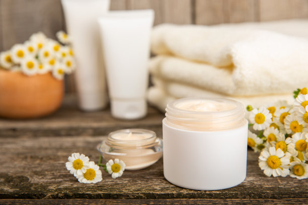 身体和护手霜与洋甘菊提取物木制背景。草本皮肤美容卫生霜。天然美容产品。木底花面霜。水疗中心的概念。图片下载
