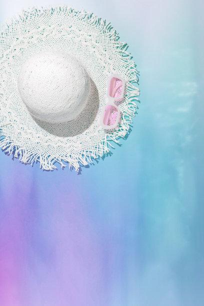 夏季垂直平躺与白色太阳帽和玫瑰色太阳镜模糊的霓虹色渐变背景。创意唯美的静物暑假写真，抽象的海水图片下载