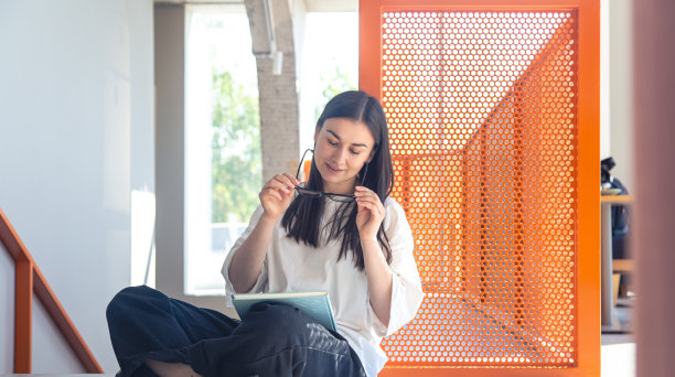 年轻女子戴着眼镜和笔记本在现代室内，学习概念。图片下载