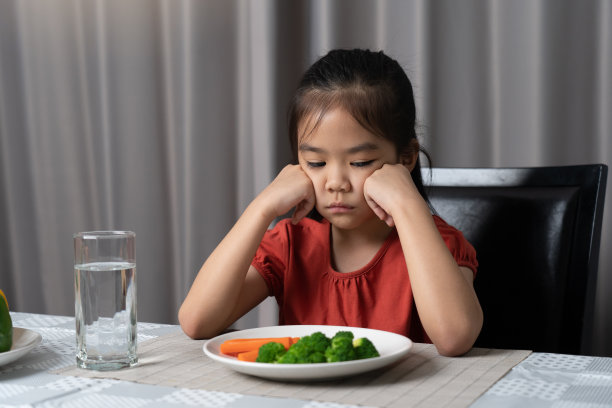 可爱的小女孩拒绝吃健康的蔬菜。孩子们不喜欢吃蔬菜。图片下载