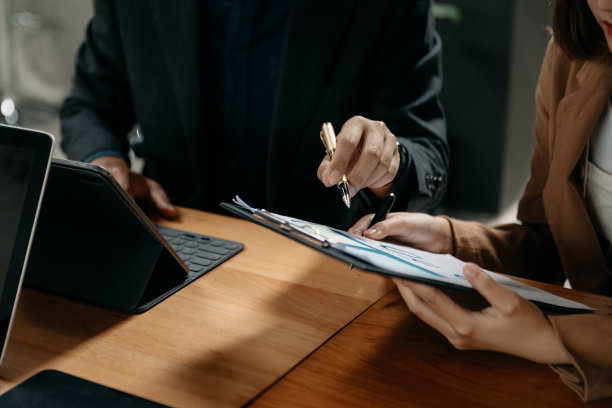 商人手持笔记本电脑和平板电脑，用社交网络图和两个同事在桌子上讨论数据作为概念图片下载