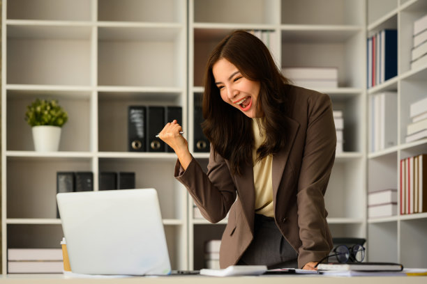 惊讶的女商人在电子邮件中读到好消息，用“是”的手势庆祝商业成功。图片下载