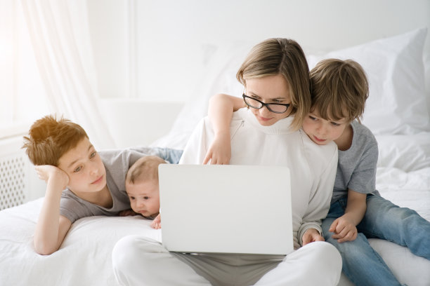 母亲在家里和孩子们一起工作，使用笔记本电脑图片下载