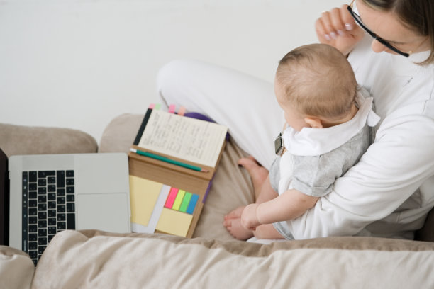 母亲带着孩子和笔记本电脑在家里工作图片下载