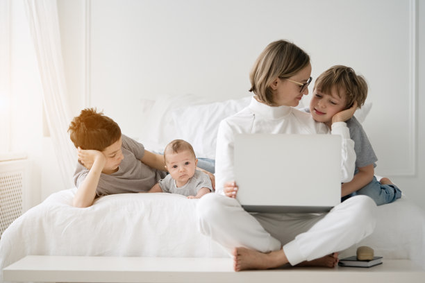 母亲在家里和孩子们一起工作，使用笔记本电脑图片下载