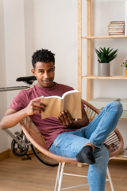 一个男人坐在客厅的椅子上看书。图片下载