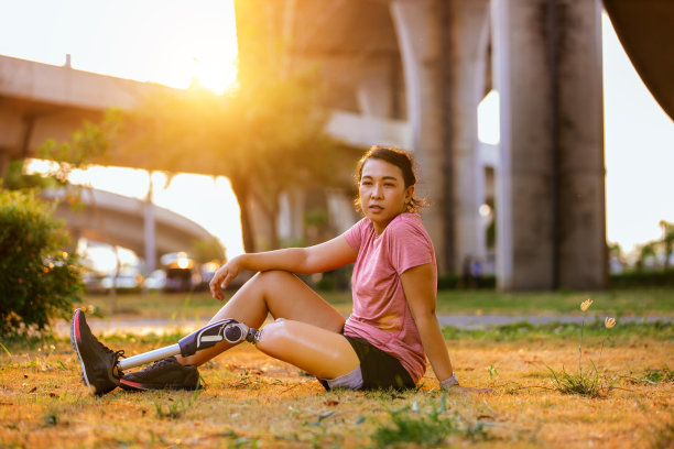 戴着义肢的运动员在公园做热身运动。戴着假肢慢跑的妇女。装有假腿的女性图片下载
