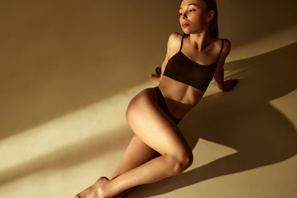 温柔、美丽、苗条的年轻女子穿着黑色棉质内衣，在温暖的阳光下摆姿势图片下载