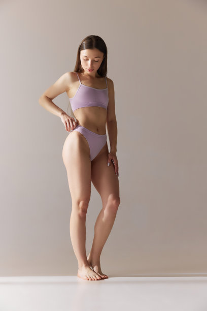 温柔的年轻女孩的全身肖像，苗条的身体，在灰色的工作室背景下穿着内衣摆姿势。吸引力图片下载