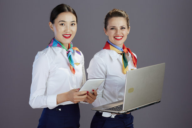 微笑的空姐女士使用笔记本电脑孤立的灰色图片下载