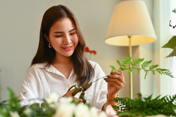 迷人的年轻女性小企业主剪树枝，创造美丽的花束她的花店。图片下载