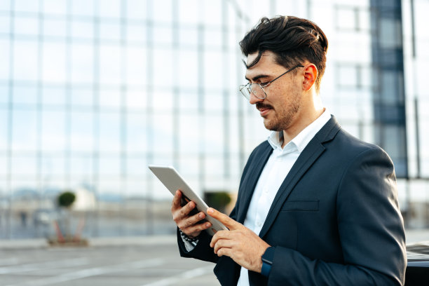 年轻的商人站在户外使用数码平板电脑图片下载