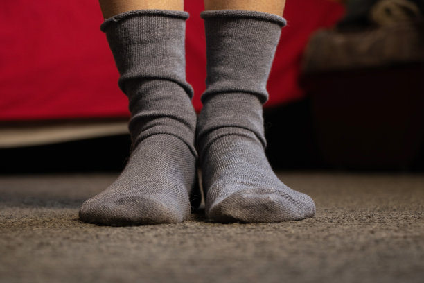 穿着蓝袜子的脚踩在公寓地板上的灰色地毯上图片下载