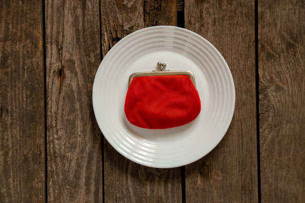 红色的钱包放在桌子上的一个白色盘子上图片下载