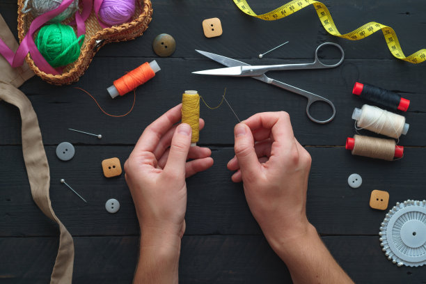用于在深色木制背景上缝合的缝纫套件。前视图。女裁缝手中的线轴图片下载