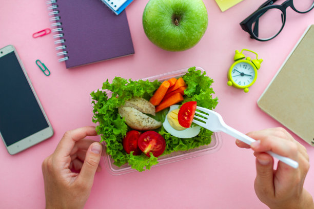 在办公室的午休时间从工作间的午餐盒里拿出健康的零食。工作时的食物。俯视图图片下载