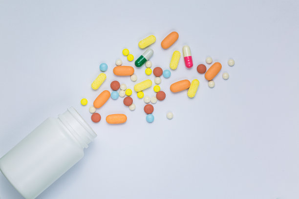 药丸和药丸瓶在白色背景，平躺(俯视图)各种类型的药丸，药片和胶囊与白色的塑料瓶容器隔离在白色背景。图片下载