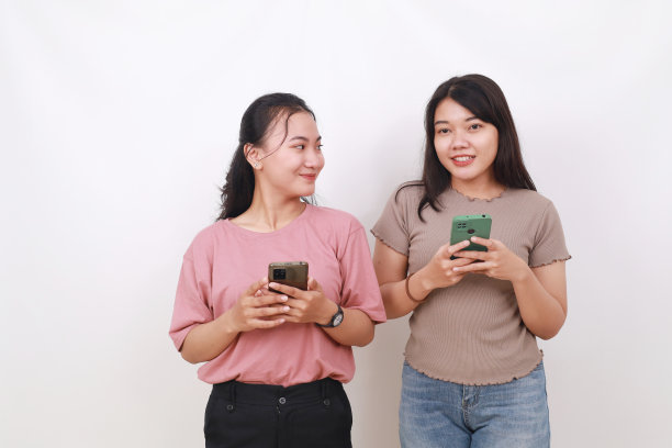 两个拿着手机的亚洲女人被隔离在白区。友谊的概念图片下载