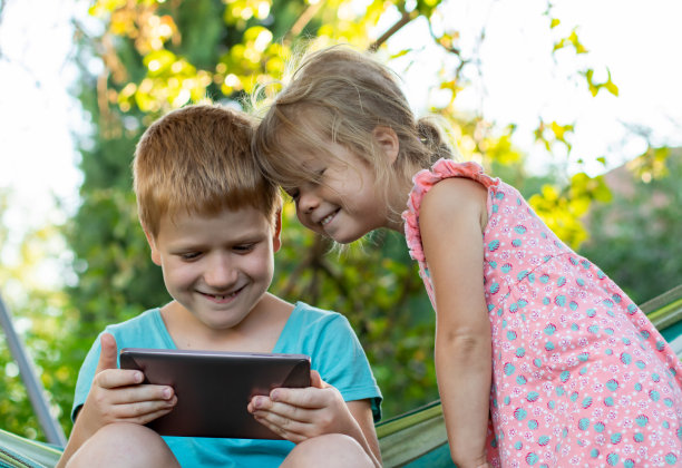 快乐的孩子，男孩和女孩在公园户外使用数字移动平板电脑图片下载