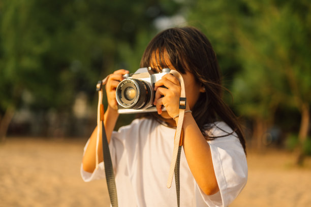 女孩在沙滩上拿着相机拍照的照片图片下载