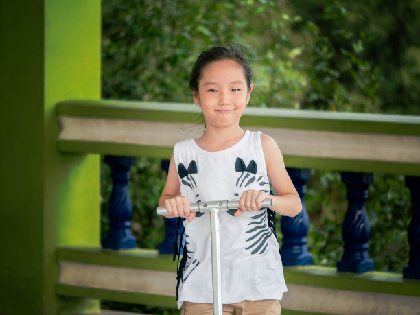 小亚洲儿童女孩在公园为孩子们踏板车图片下载