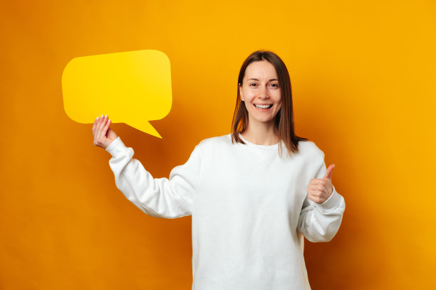 英俊的微笑女子正举着大拇指和一个黄色的演讲泡泡。图片下载