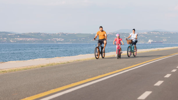 妈妈、爸爸和孩子在海边骑车图片下载