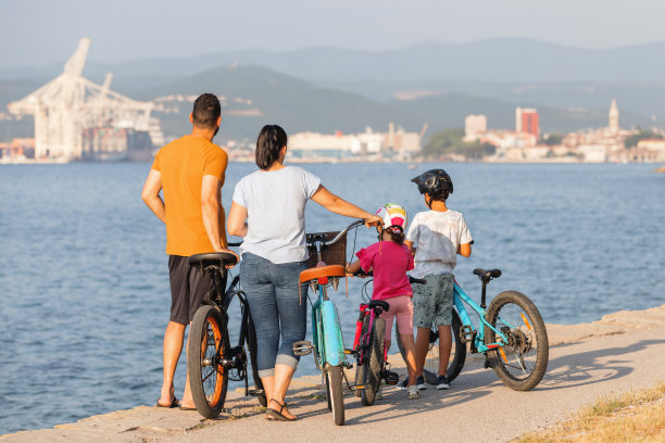 一家人骑着自行车在海边欣赏日落，后景图片下载