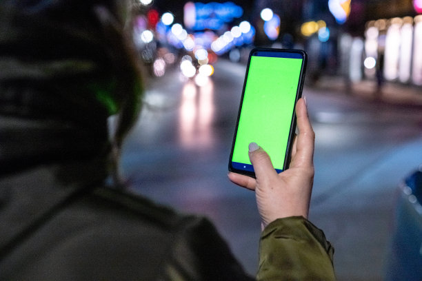 晚上在外面玩手机的年轻快乐的女人。图片下载